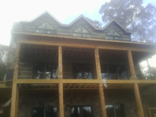 Dormers and porch framing on a large log home under construction — Roof Coating work by our crew in Mill Creek