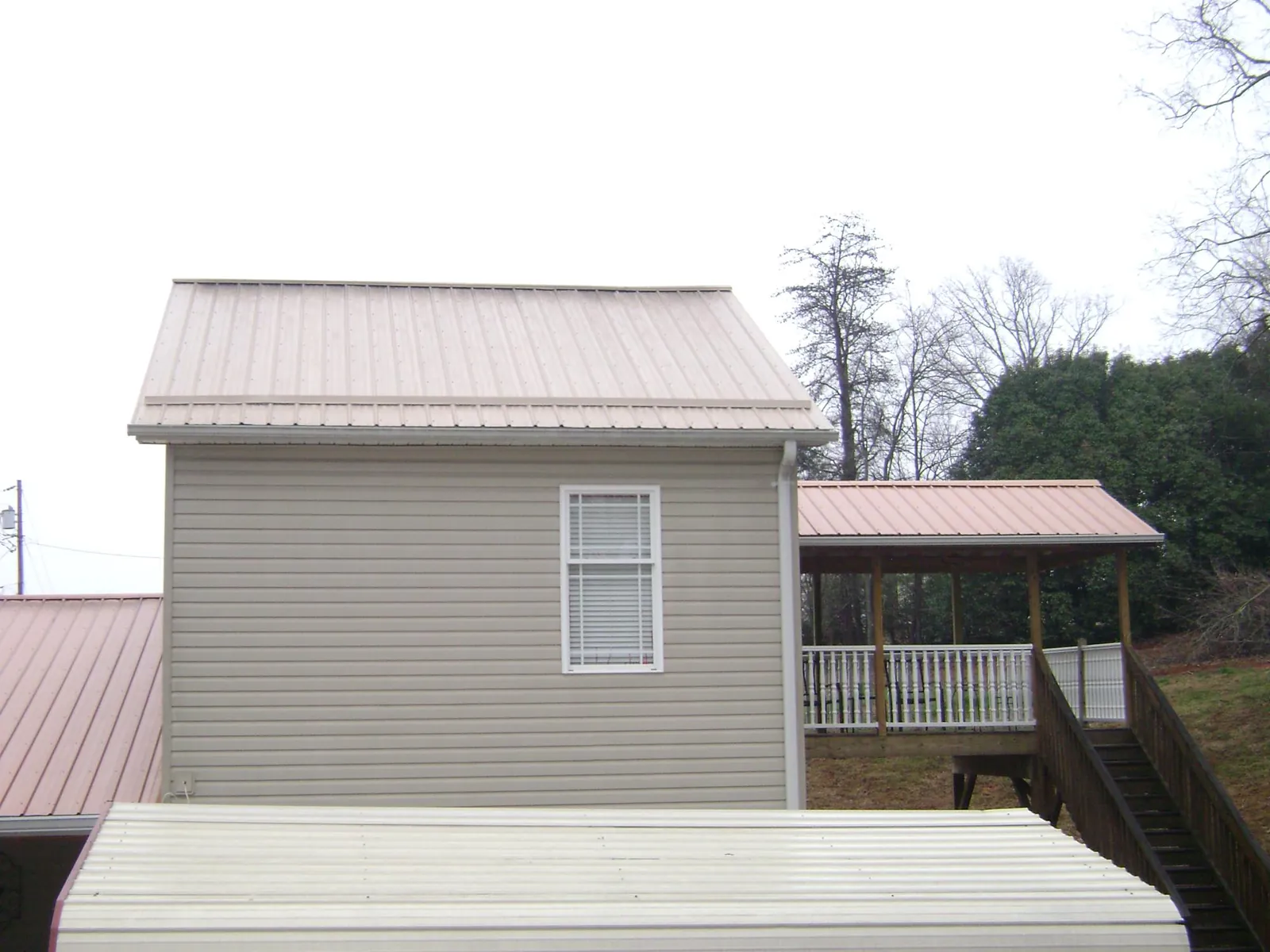 Tan metal roofs on a two story addition and attached porch, from a Roof Replacement job in Mill Creek